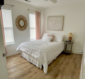 Une chambre à coucher avec un grand lit, une table de chevet avec une lampe, une œuvre d’art accrochée au mur et un miroir décoratif.