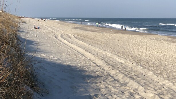 A wide sandy beach with gentle waves, clear skies, and sparse vegetation. - Spacious and Bright townhome, steps to the beach, pet friendly* (Carolina Beach)