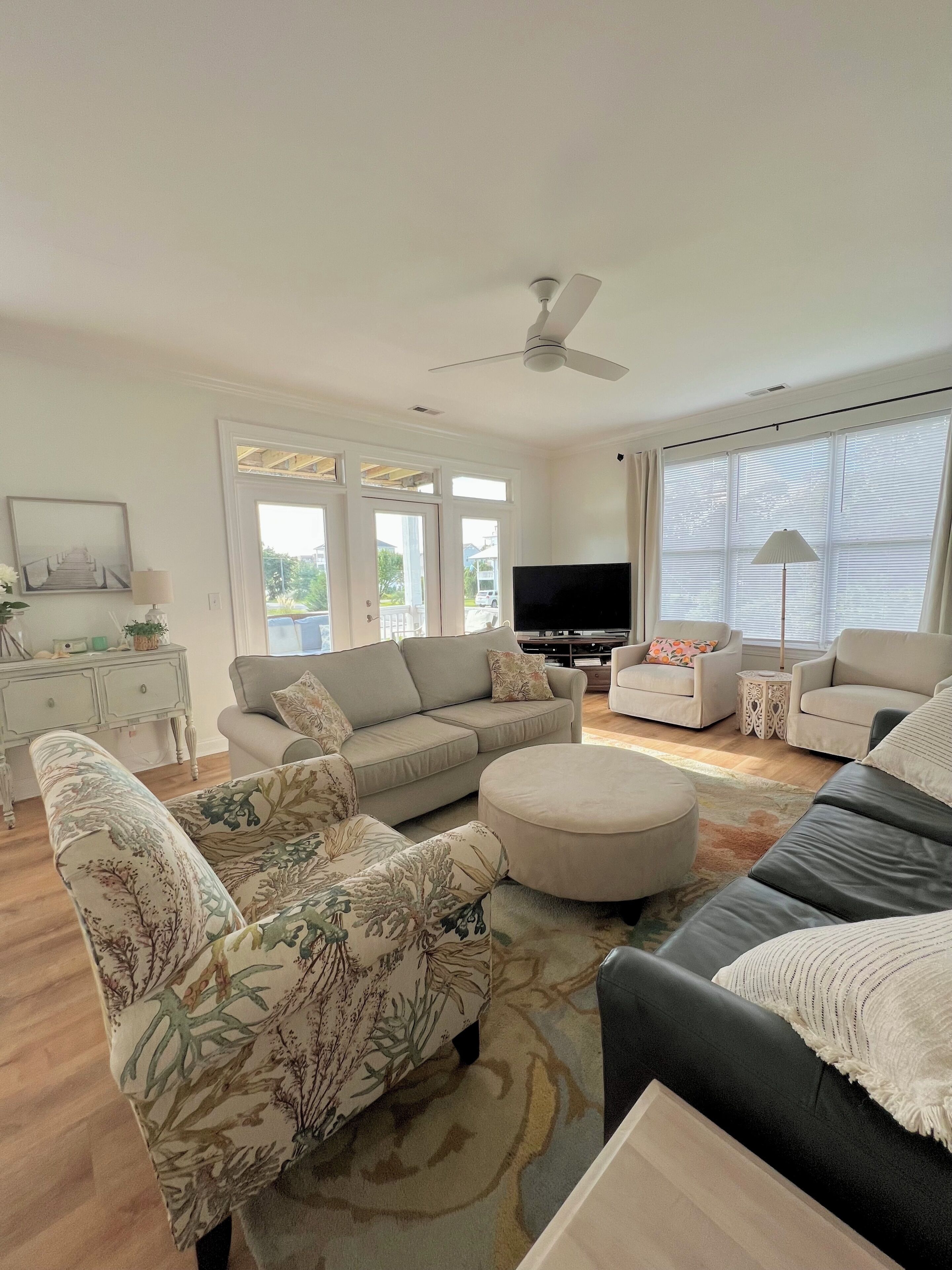 A living room with a sofa, ottoman, and a television.