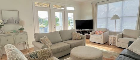 A living room with a sofa, ottoman, and a television.