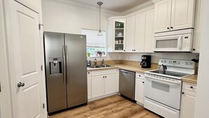 A kitchen with white cabinets, a stainless steel refrigerator, a microwave, an oven, and a dishwasher. - Spacious and Bright townhome, steps to the beach, pet friendly* (Carolina Beach)