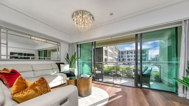 A modern living room with a white sofa, a round coffee table, and a large window offering a view of a cityscape.