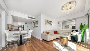 A modern living room with a dining area, a sofa, a coffee table, and a chandelier.