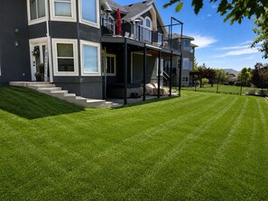 A two-story house with a balcony, a well-maintained lawn, and a clear sky. - Private Hot Tub & Sunset Views - 3 BR Guest Suite (North Salt Lake)
