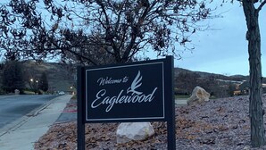 Placa de boas-vindas para Eaglewood com montanhas ao fundo.