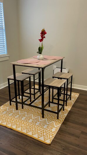 A cozy dining area with a wooden table, two chairs, and a potted orchid.