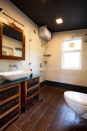 Features a sleek bathroom with a large vessel sink, wooden vanity, and toilet.