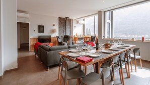 A modern living room with a dining area, large windows, and a view of the city. - Experience the Exception at Chalet La Source: Comfort, Relaxation and Magnificent Views (Cauterets)