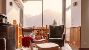 A modern living room with a large window, a bookshelf, and two armchairs. - Experience the Exception at Chalet La Source: Comfort, Relaxation and Magnificent Views (Cauterets)