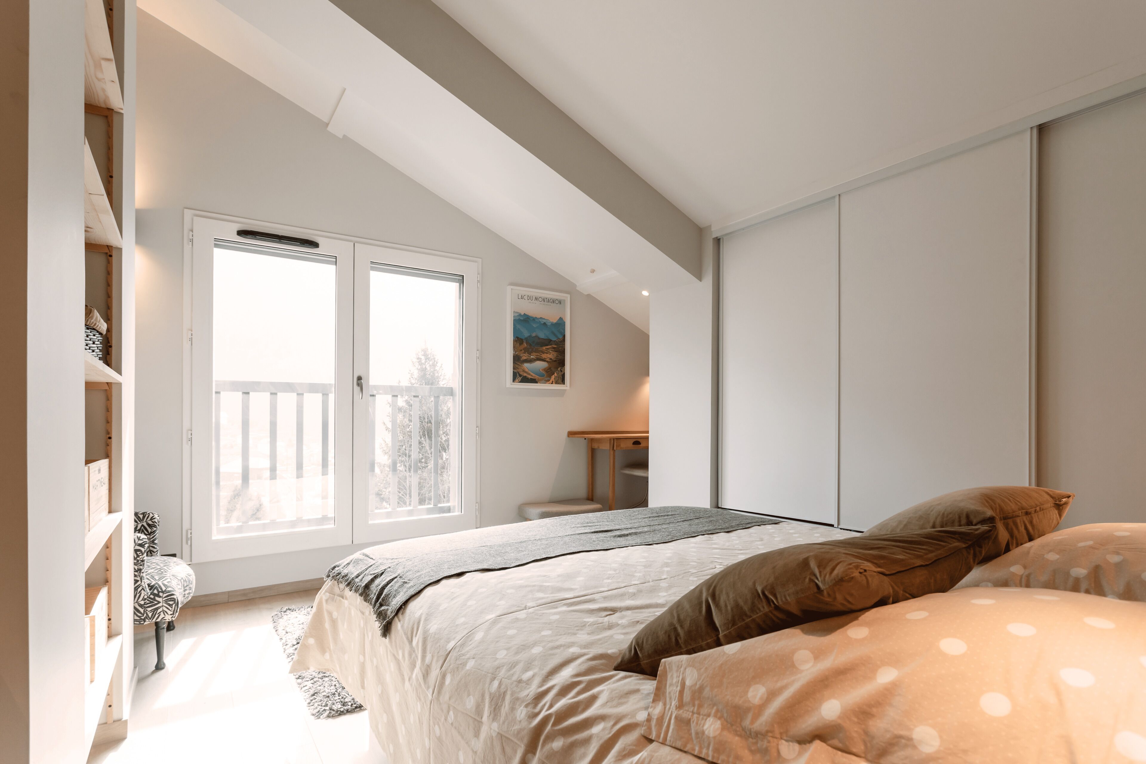 Une chambre à coucher avec un lit, une fenêtre, un bureau et une bibliothèque.