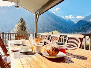 A wooden table set with breakfast items and a view of snow-capped mountains. - Experience something extraordinary at Chalet La Source: comfort, relaxation, and magnificent views (Cauterets)