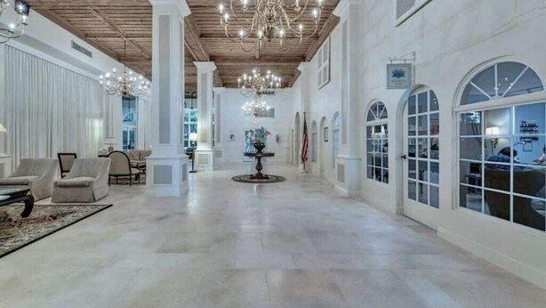 Un'ampia hall con soffitto alto, lampadari e un tavolo centrale.