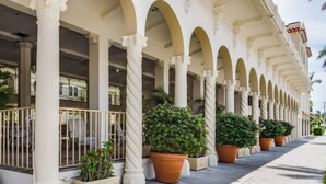 Un edificio con una serie di archi sorretti da colonne, aree salotto all'aperto e piante in vaso.