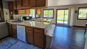A spacious kitchen with wooden cabinets, a large island, and a dishwasher. - Sleeps 18!  Heated pool and lake access. (Mears)