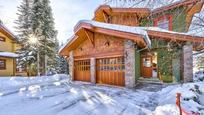 Ein zweigeschossiges Haus mit Holztür zur Garage, Naturstein-Fassade und einem verschneiten Einfahrt.
