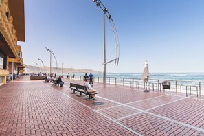 A paved promenade with benches and street lamps, overlooking a body of water.