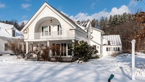 Una casa blanca de dues plantes amb un balcó, envoltada de neu.