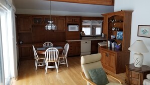A kitchen with wooden cabinets, a dining table with chairs, a built-in oven, and a microwave. - Lake Access! 5 minutes to the dunes! (Mears)