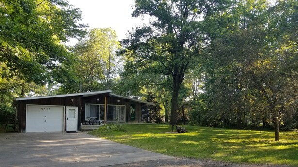 A single-story building with a garage, a covered porch, and a lawn. - Lake Access! 5 minutes to the dunes! (Mears)
