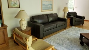A living room with a leather sofa, two armchairs, a wooden coffee table, a patterned rug, and two lamps. - Lake Access! 5 minutes to the dunes! (Mears)