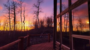 A wooden deck with a glass railing overlooking a forest at sunset. - Luxurious Mountain Retreat - Minutes from Park City and Deer Valley (Coalville)