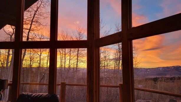 A room with a large window offering a view of a sunset over a mountainous landscape. - Luxurious Mountain Retreat - Minutes from Park City and Deer Valley (Coalville)