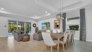 A spacious living room with a dining area, large windows, and a view of a pool. - Gated Resort Community Pool Home (Estero)