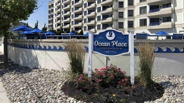 Schild für Ocean Place Condominium, im Hintergrund ein mehrstöckiges Gebäude.