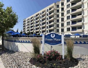 Placa para Ocean Place Condominium, com um edifício de vários andares ao fundo.