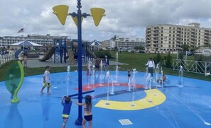 Uma área de recreação aquática com vários jatos d'água, um escorregador e um parquinho.