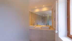Casa de banho moderna com um espelho grande, duas pias e um chuveiro.