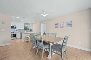A spacious kitchen with white cabinets, a central island, and a dining area with a wooden table and chairs.