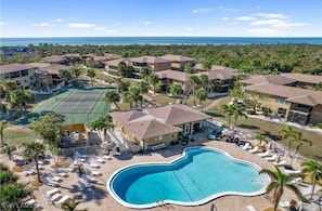 A resort with a large swimming pool, tennis courts, and beachfront views.
