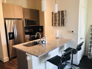 Kitchen area with bar stools and all major appliances  - Modern Sanitized 1 Bedroom Condo/ 1st Floor Private Parking (Arlington)