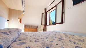 Een slaapkamer met een bed, een raam en uitzicht op de omgeving.