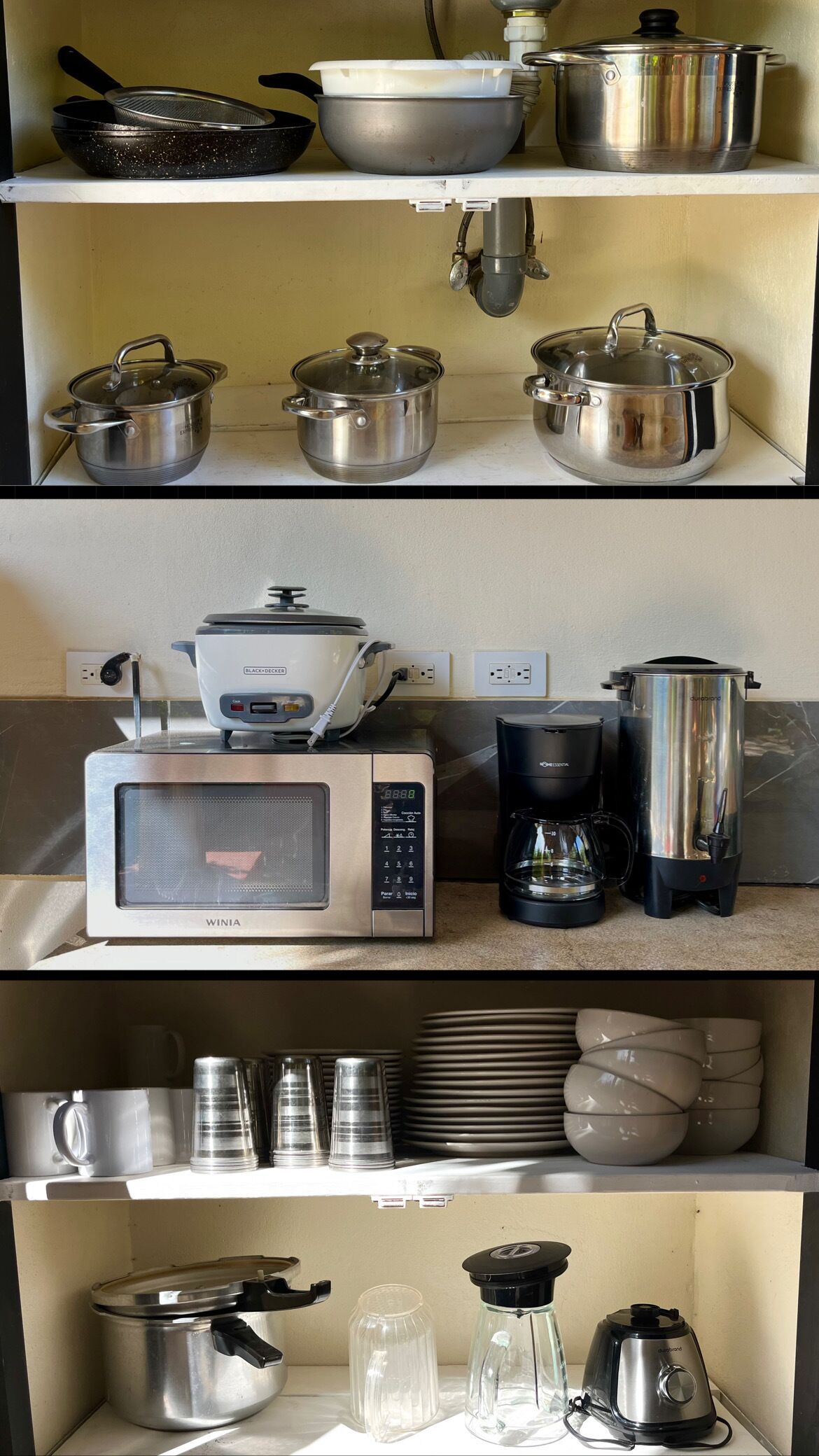 A kitchen with stainless steel cookware, a microwave, a coffee maker, and various glassware.