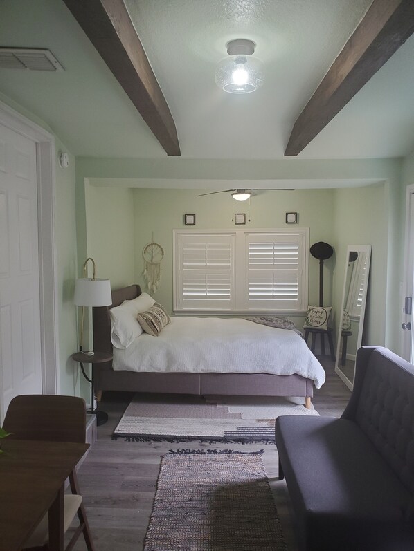 Un dormitorio con cama, mesitas de noche, espejo y ventilador de techo.
