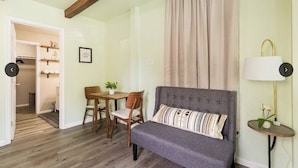 Un salon avec un canapé gris, des chaises en bois, une petite table sur laquelle est posée une plante, et une lampe sur une table d’appoint.