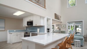 Een ruime keuken met een groot eiland, witte kastjes en een blauwe spatwand.