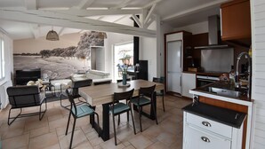 Eine moderne Küche mit Essbereich, ausgestattet mit einer großen Kochinsel, weißen Schränken und Blick auf eine verschneite Landschaft durch das Fenster.