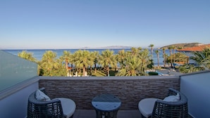 A balcony with wicker furniture overlooking a sea view, palm trees, and a distant mountain range. - My Marina Select Hotel (Datça)