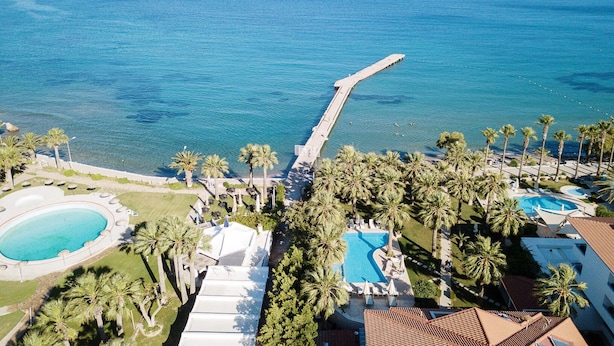 A resort with a long pier extending into the sea, a swimming pool, and palm trees. - My Marina Select Hotel (Datça)
