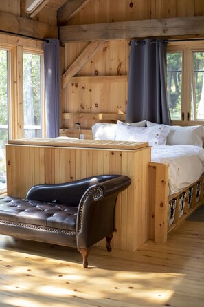 Un dormitorio de cabaña de madera con una cama, un sofá de cuero y un escritorio de madera.