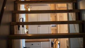 A wooden staircase with metal handrails leading to a room with a kitchen in the background. - Cooper Bay Lakeside Escape – 322ft frontage, quiet, stunning west views! (Bracebridge)