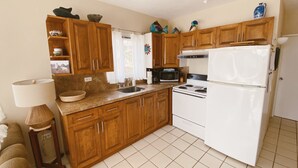 A kitchen with wooden cabinets, a white refrigerator, a stove, and a microwave. - Beachfront Retreat with Convenient Access to Shops, Dining, and More (San José del Cabo)