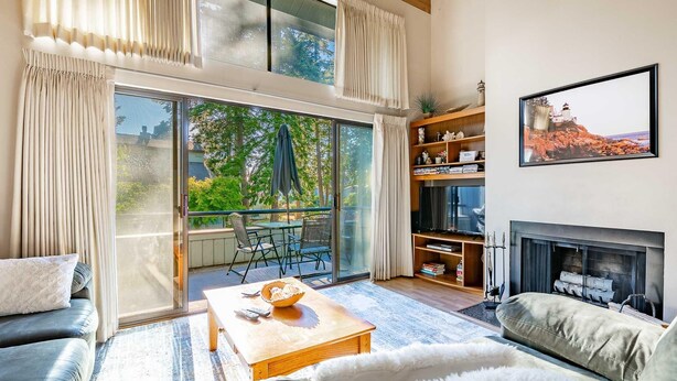 A spacious living room with a large sliding glass door leading to a balcony, a fireplace, and a bookshelf. - Indoor Pool, steps from beach  JL304 (Birch Bay)