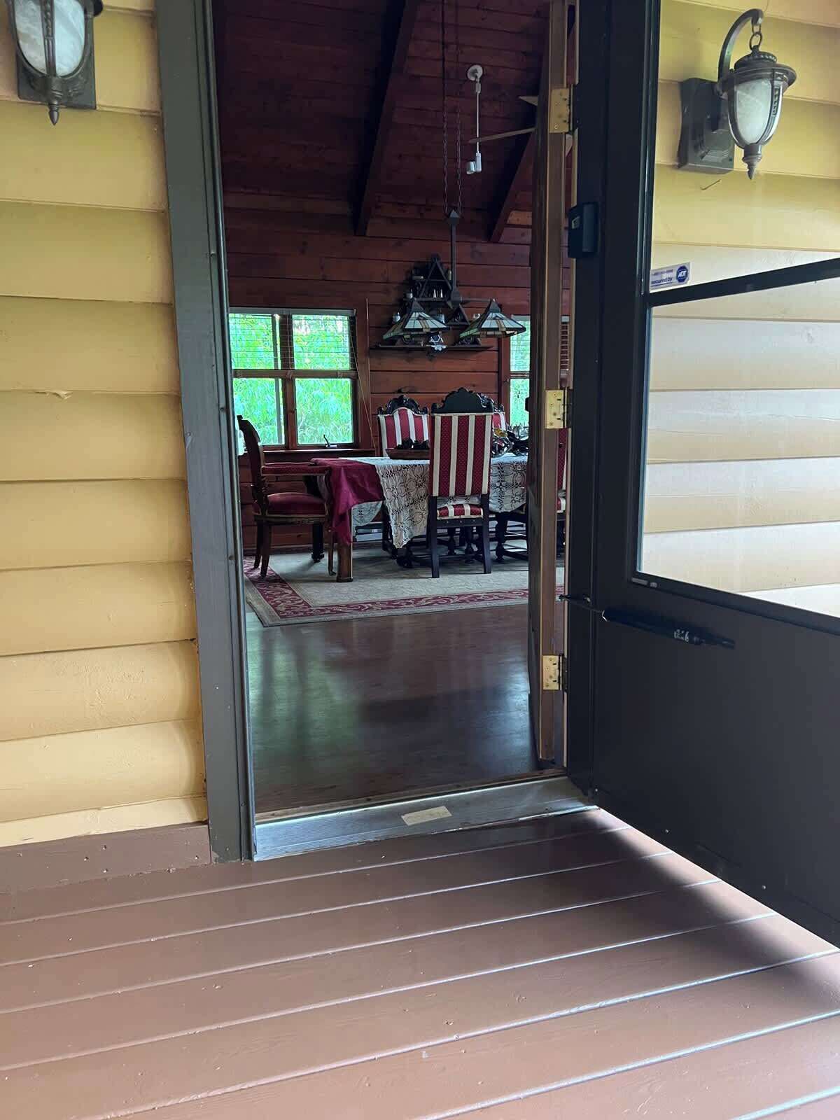 A wooden interior with a dining area, a staircase, and a door leading outside.