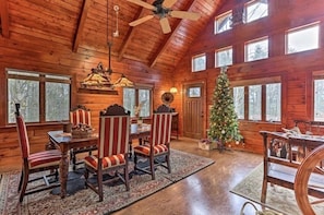 Cozy cabin-style interior with a high ceiling, dining area, and large window.