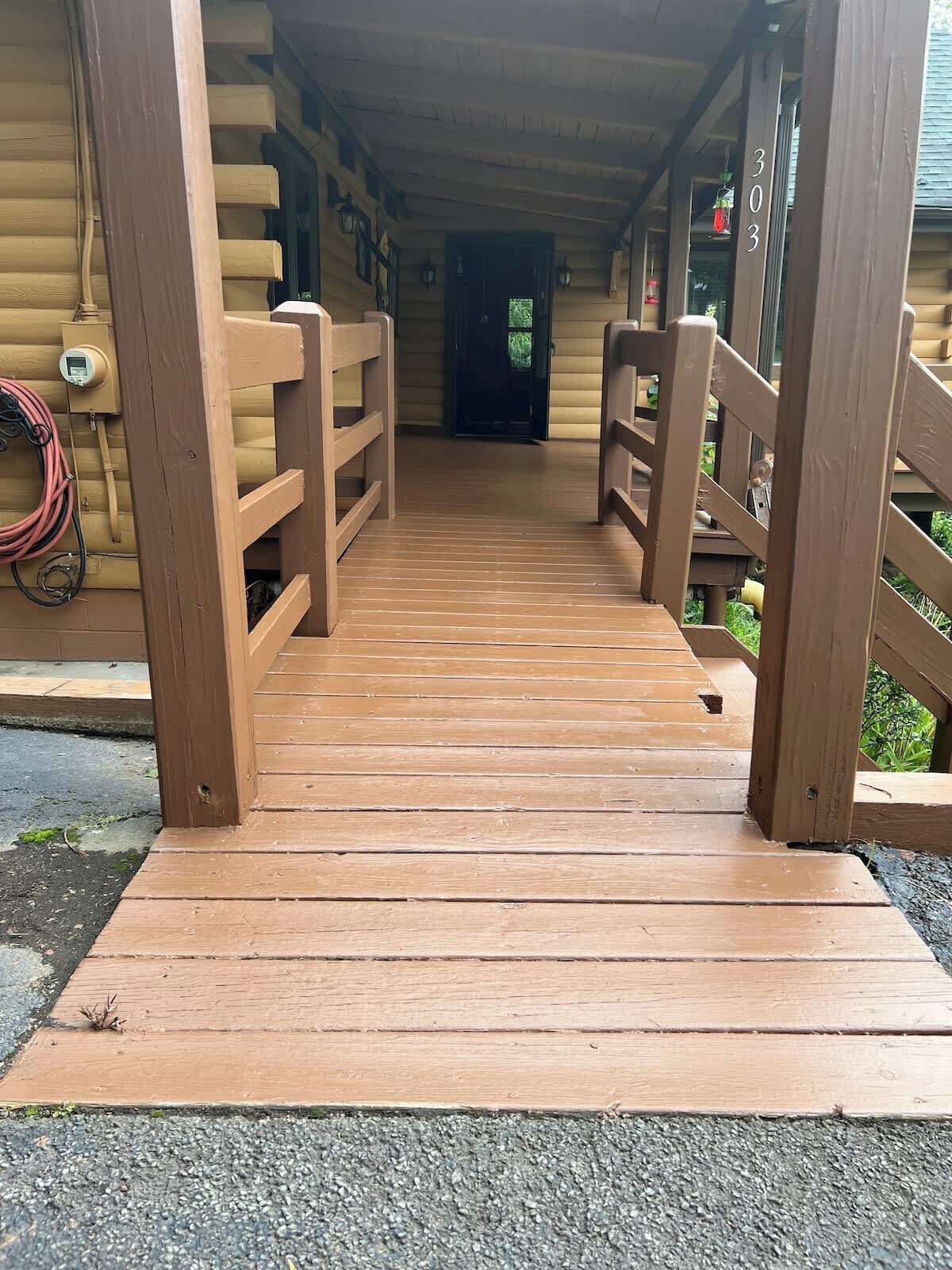 Un pont en bois mène à une cabane en rondins sur laquelle on peut voir le numéro « 303 » peint sur le mur.