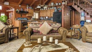 L’intérieur d’un chalet rustique est doté d’un escalier en bois, d’un salon confortable avec un canapé et une table basse, ainsi que d’une cuisine avec des armoires en bois et un réfrigérateur.